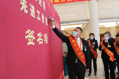 图为全国劳动模范李凤明在签名墙上签字